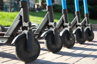 Many modern electric scooters parked on city street, closeup. Rental service