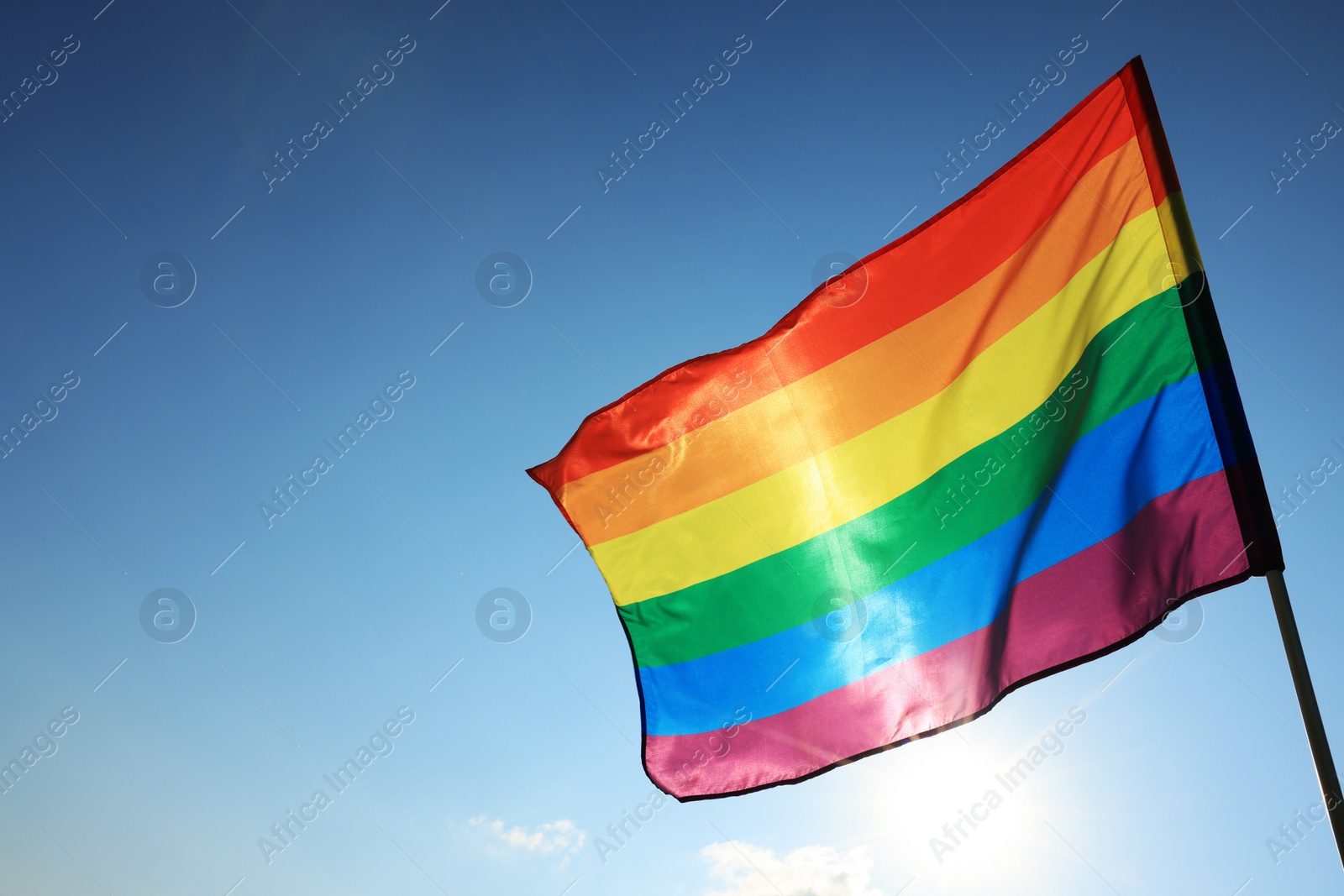 Photo of Bright LGBT flag fluttering against blue sky, space for text. Lesbian concept