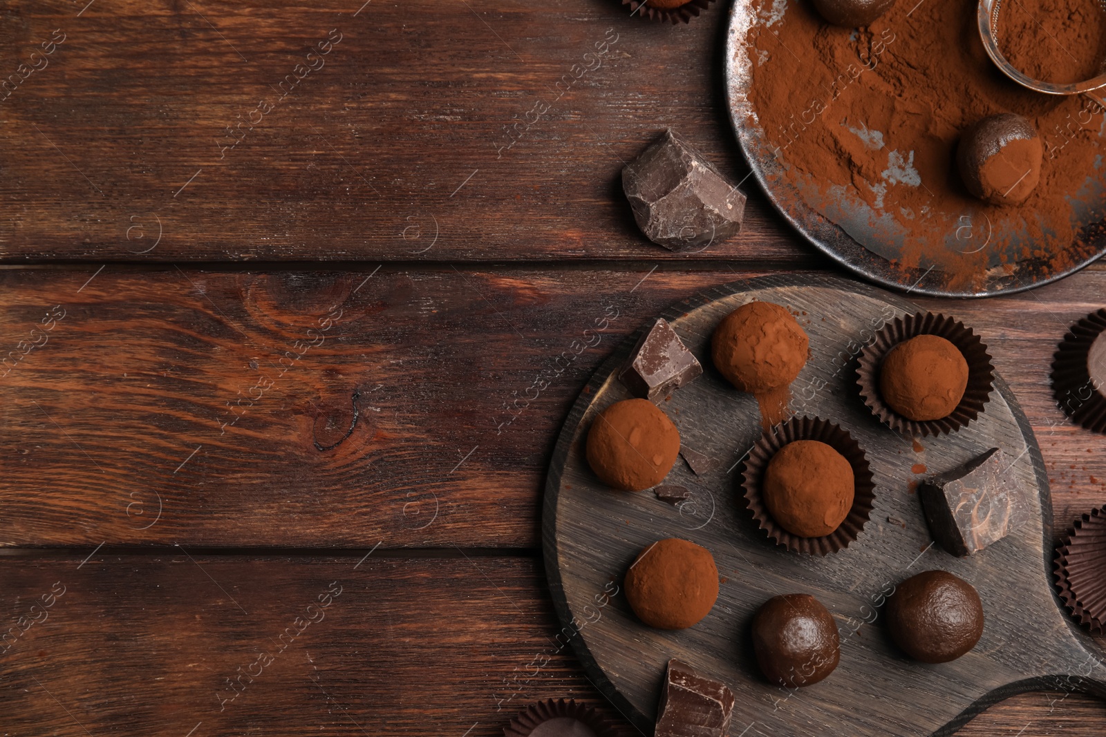 Photo of Delicious chocolate truffles powdered with cocoa on wooden table, flat lay. Space for text