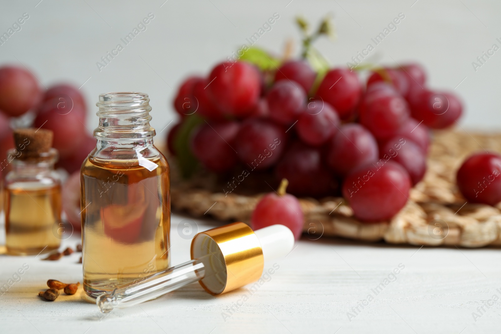 Photo of Bottle of natural grape seed oil on white wooden table, space for text. Organic cosmetic