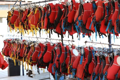 Rack with life jackets outdoors on sunny day