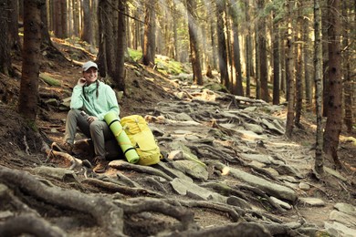 Photo of Tourist with bottle of water and backpack resting in mountain forest