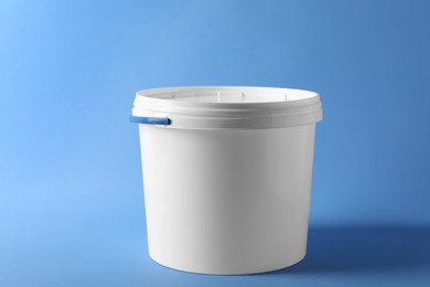 Photo of One plastic bucket with lid on light blue background