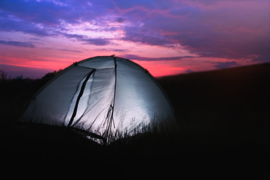 Image of Modern camping tent glowing in twilight, outdoors