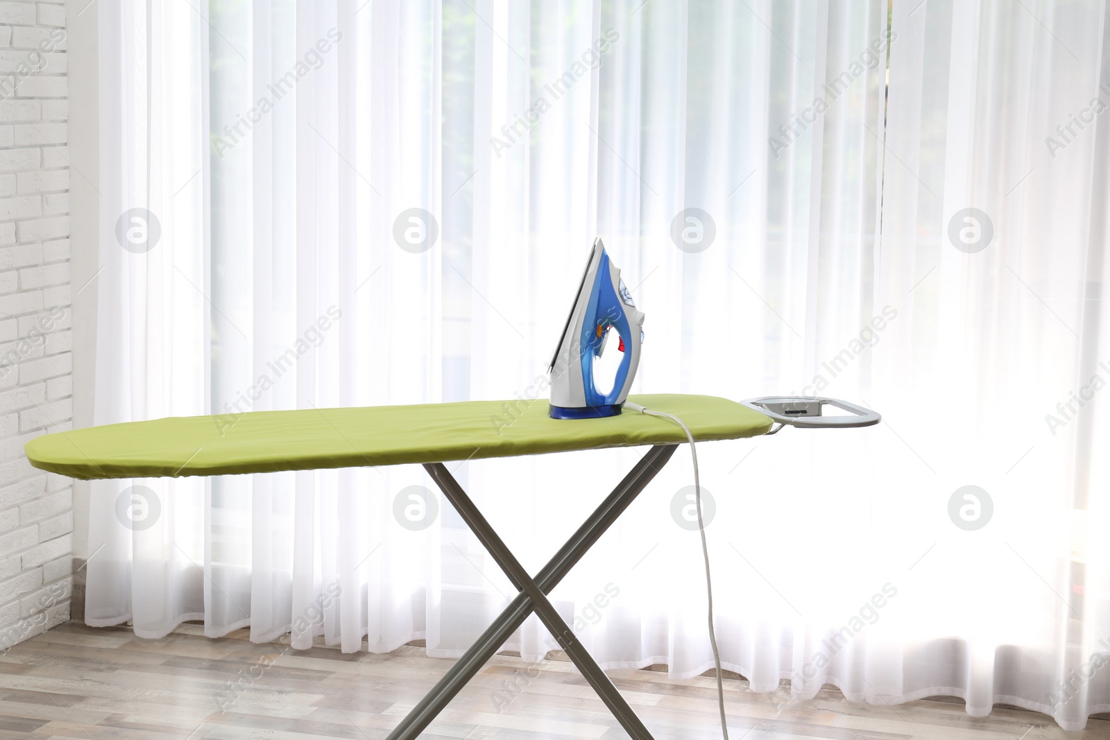 Photo of Board with modern iron at home. Laundry day