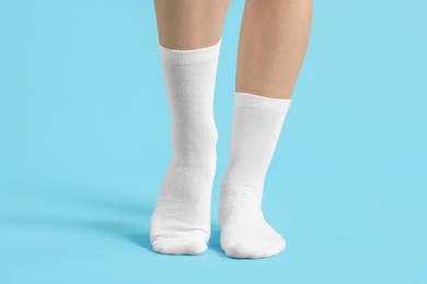 Photo of Woman in stylish white socks on light blue background, closeup