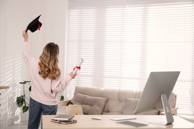 Photo of Happy student with graduation hat and diploma at workplace in office, back view