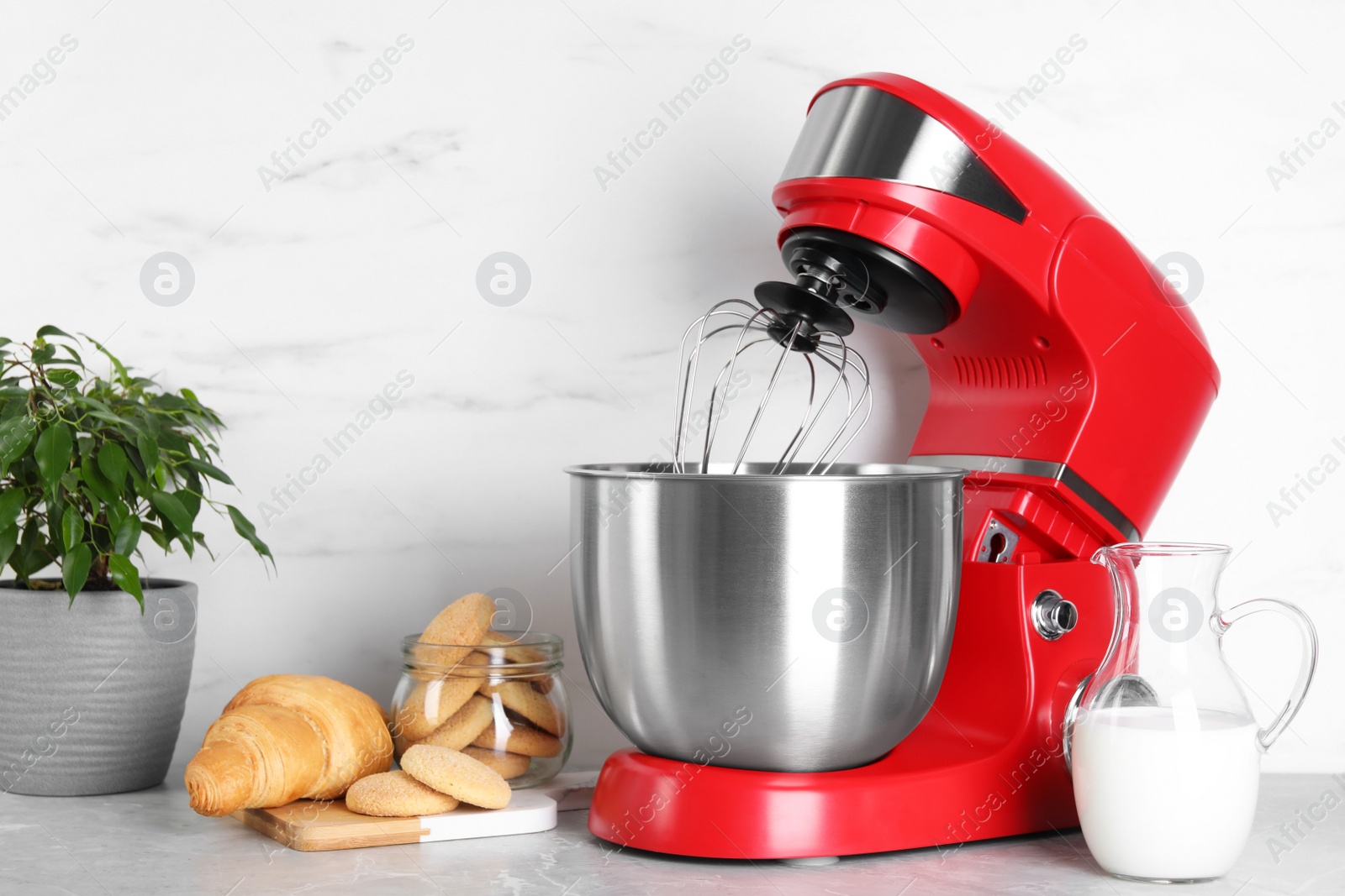 Photo of Modern red stand mixer, croissant and cookies on light gray marble table