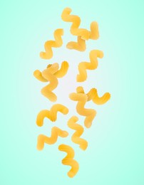 Image of Raw cavatappi pasta falling on aquamarine background
