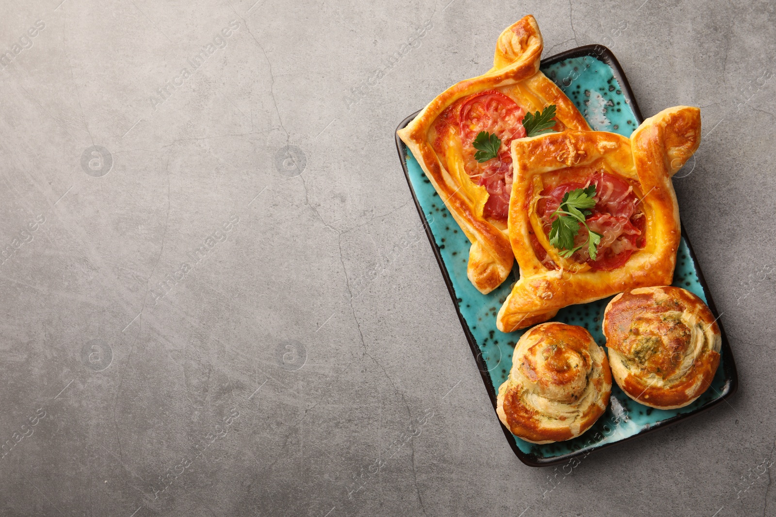 Photo of Different delicious puff pastry with tasty filling on grey table, top view. Space for text