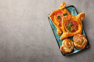 Different delicious puff pastry with tasty filling on grey table, top view. Space for text