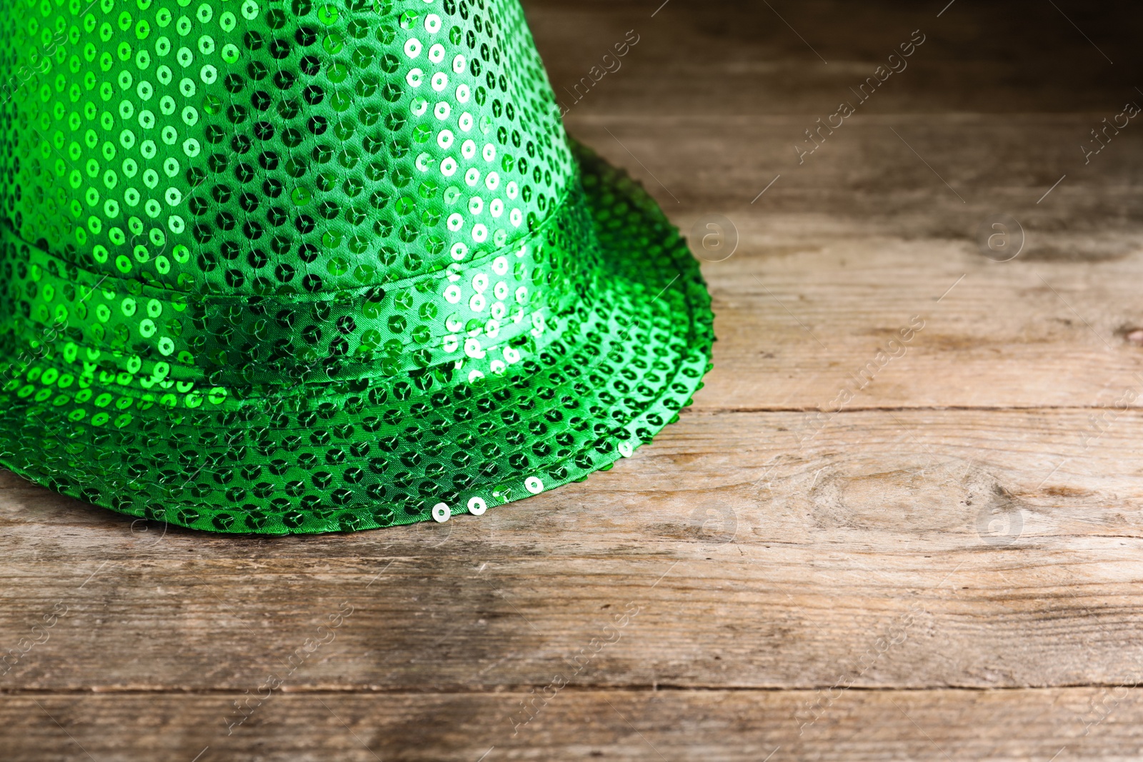 Photo of Green leprechaun hat on wooden table, space for text. St. Patrick's Day celebration