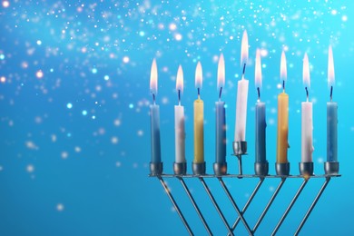 Image of Hanukkah celebration. Menorah with burning candles on light blue background, closeup. Space for text