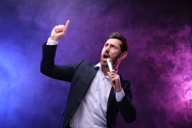 Photo of Emotional man with microphone singing in neon lights