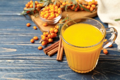 Fresh sea buckthorn tea on blue wooden table. Space for text