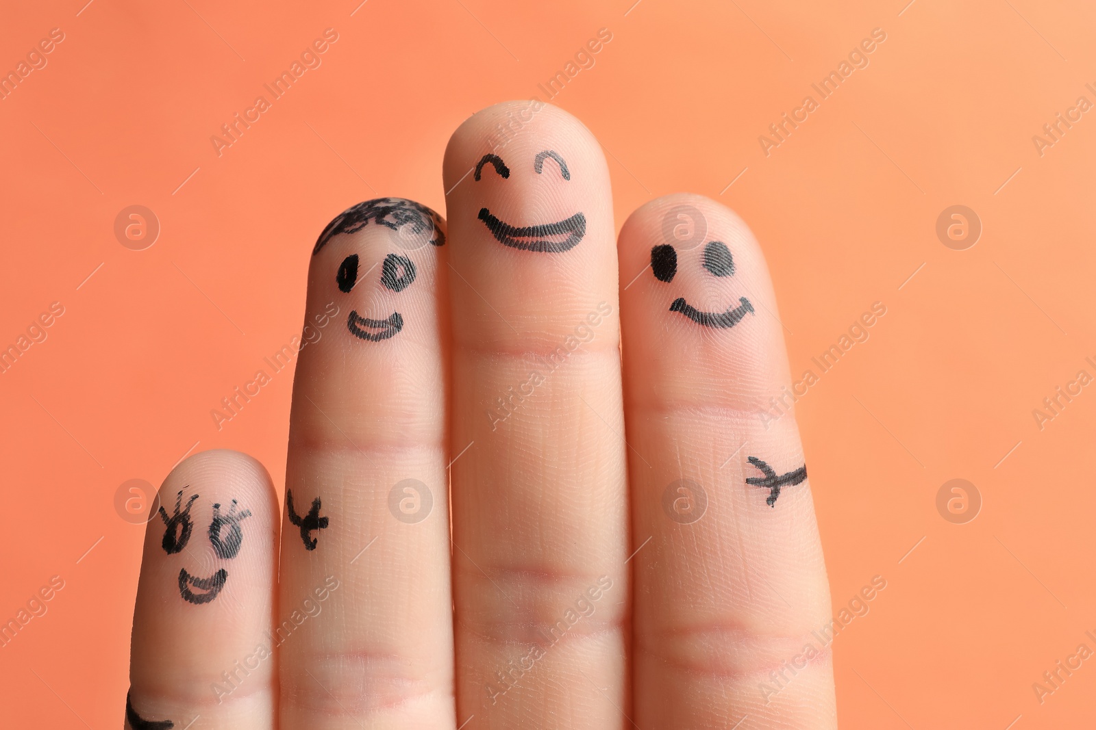 Photo of Fingers with drawings of happy faces against color background. Unity concept