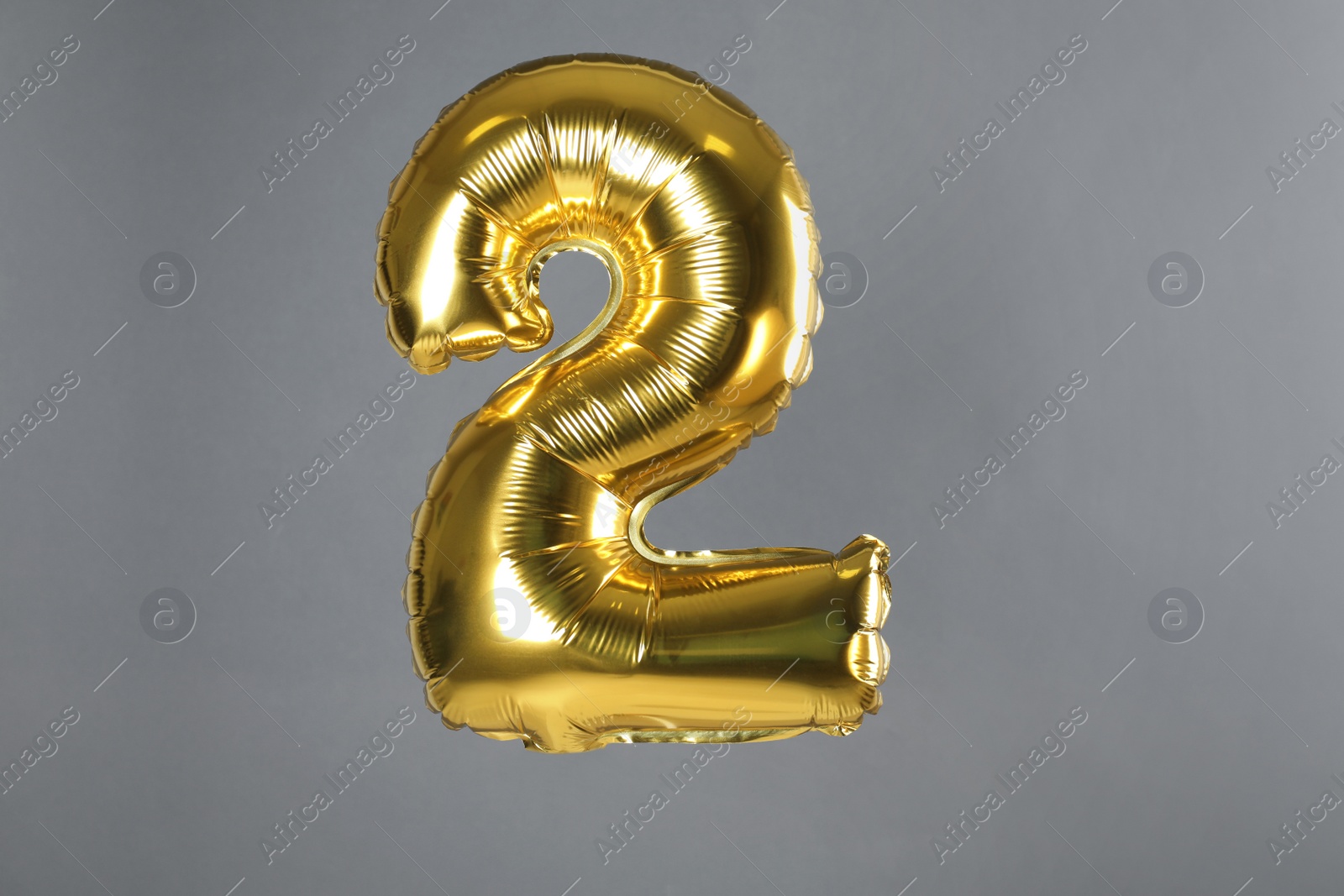 Photo of Golden number two balloon on grey background