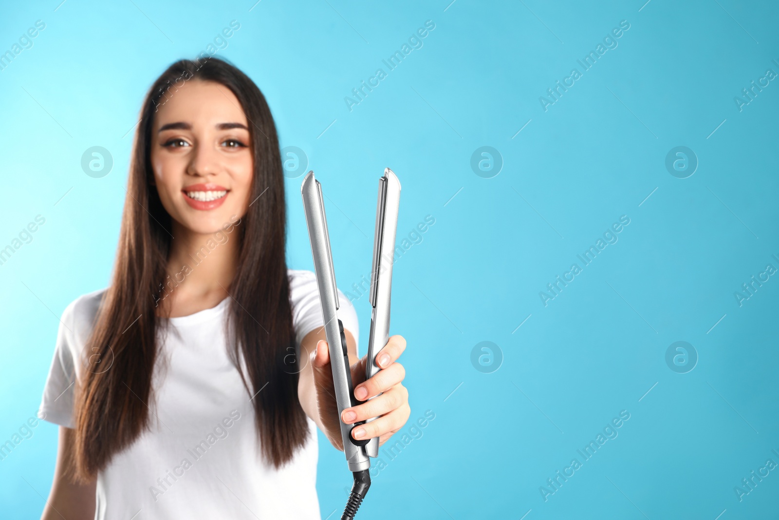 Photo of Happy woman with hair iron on color background. Space for text