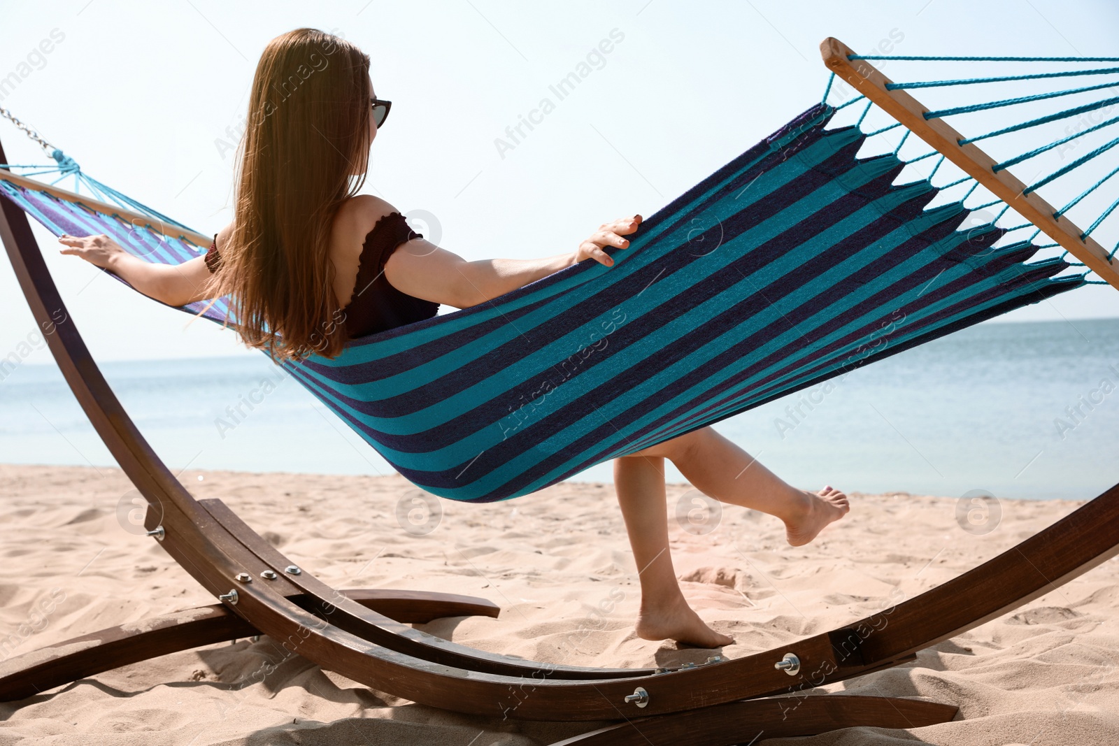 Photo of Young woman relaxing in hammock on beach