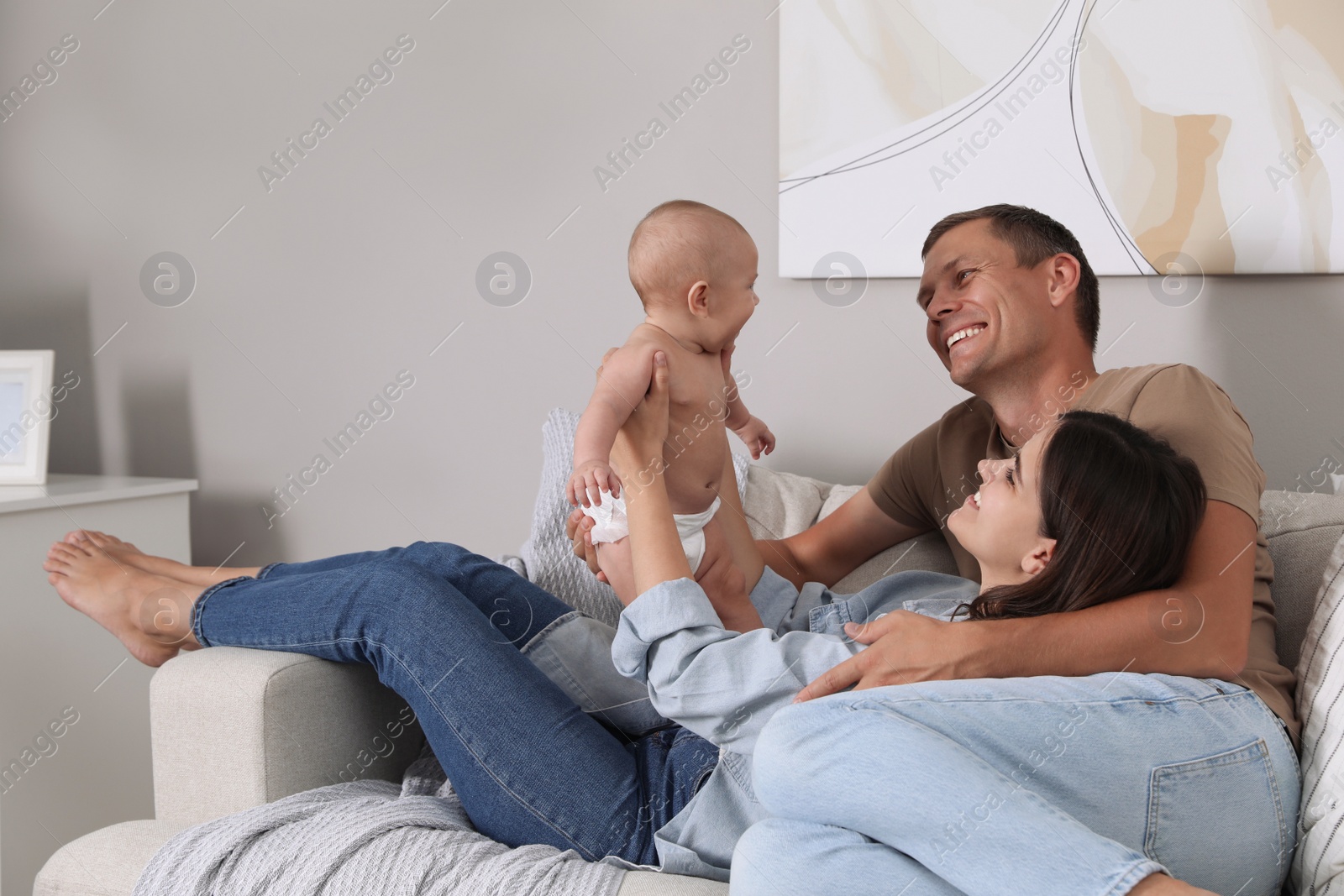 Photo of Happy family with their cute baby on sofa in living room