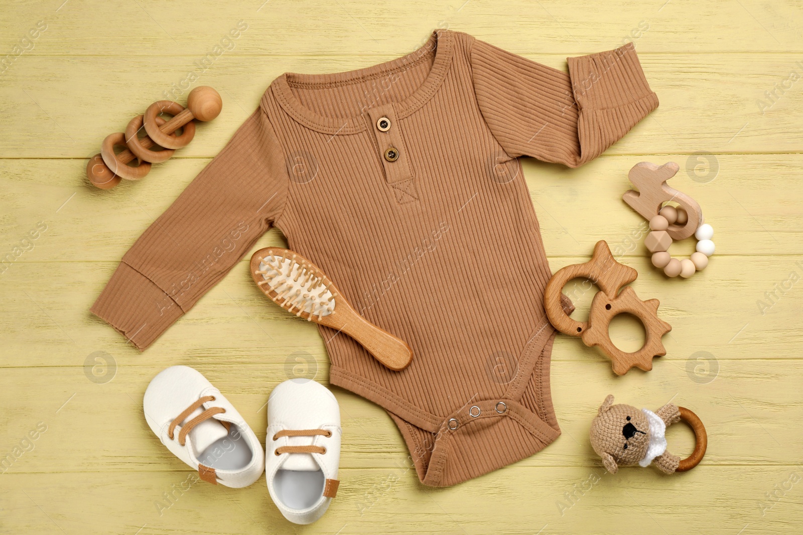 Photo of Flat lay composition with baby clothes and accessories on yellow wooden table