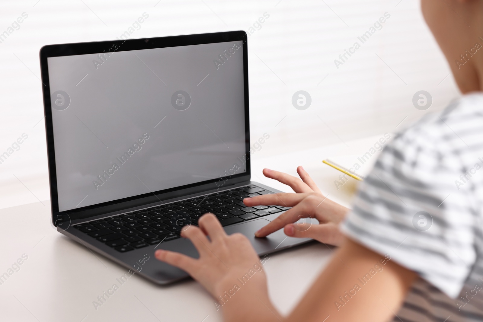 Photo of E-learning. Girl using laptop during online lesson at table indoors, closeup