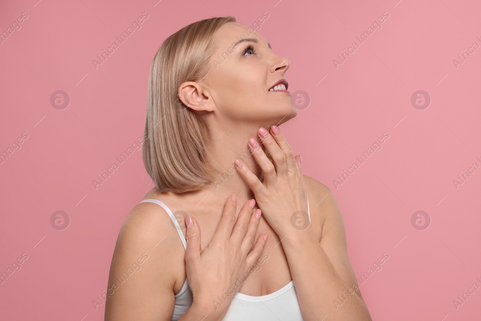 Photo of Beautiful woman touching her neck on pink background