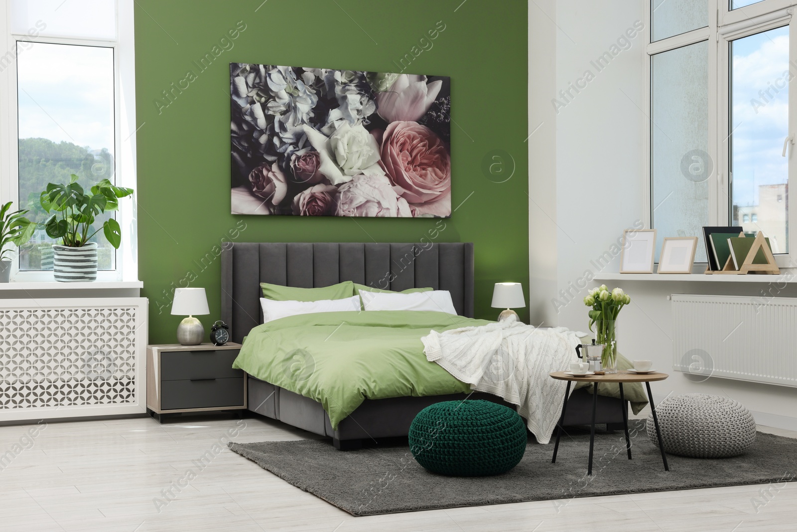 Photo of Stylish bedroom with comfortable bed, bedside tables and vase of tulips. Interior design