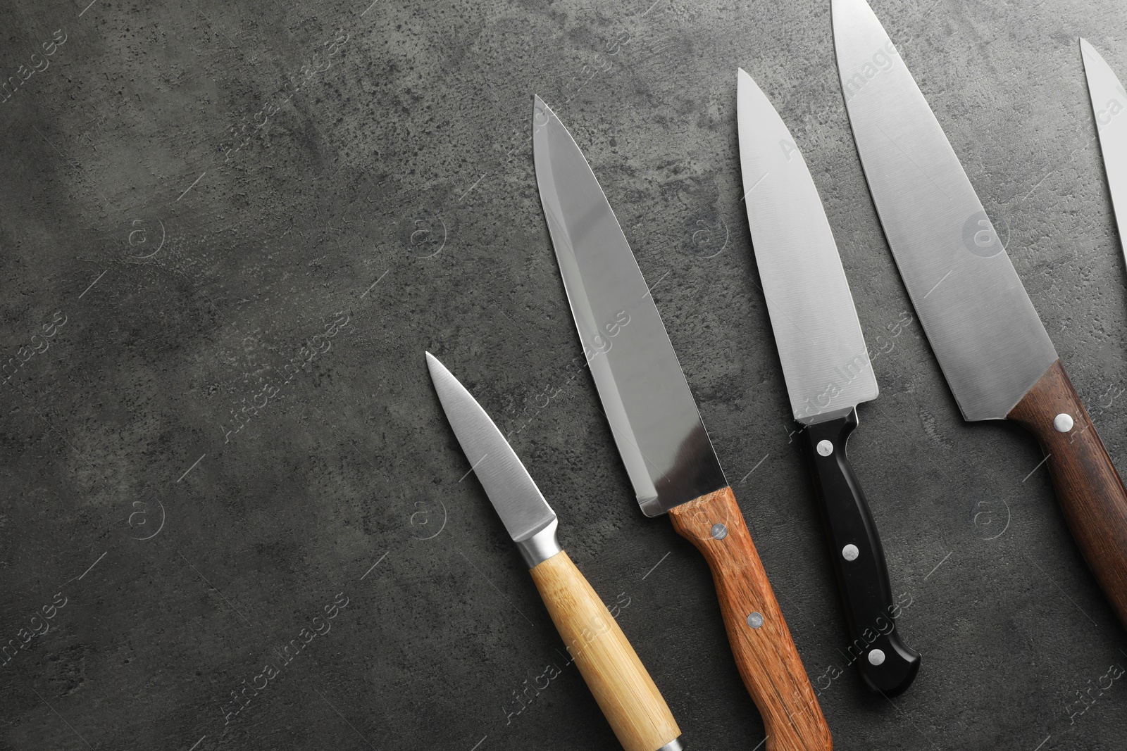 Photo of Many different knives on grey textured table, flat lay. Space for text