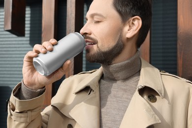 Photo of Handsome man drinking from tin can outdoors, closeup