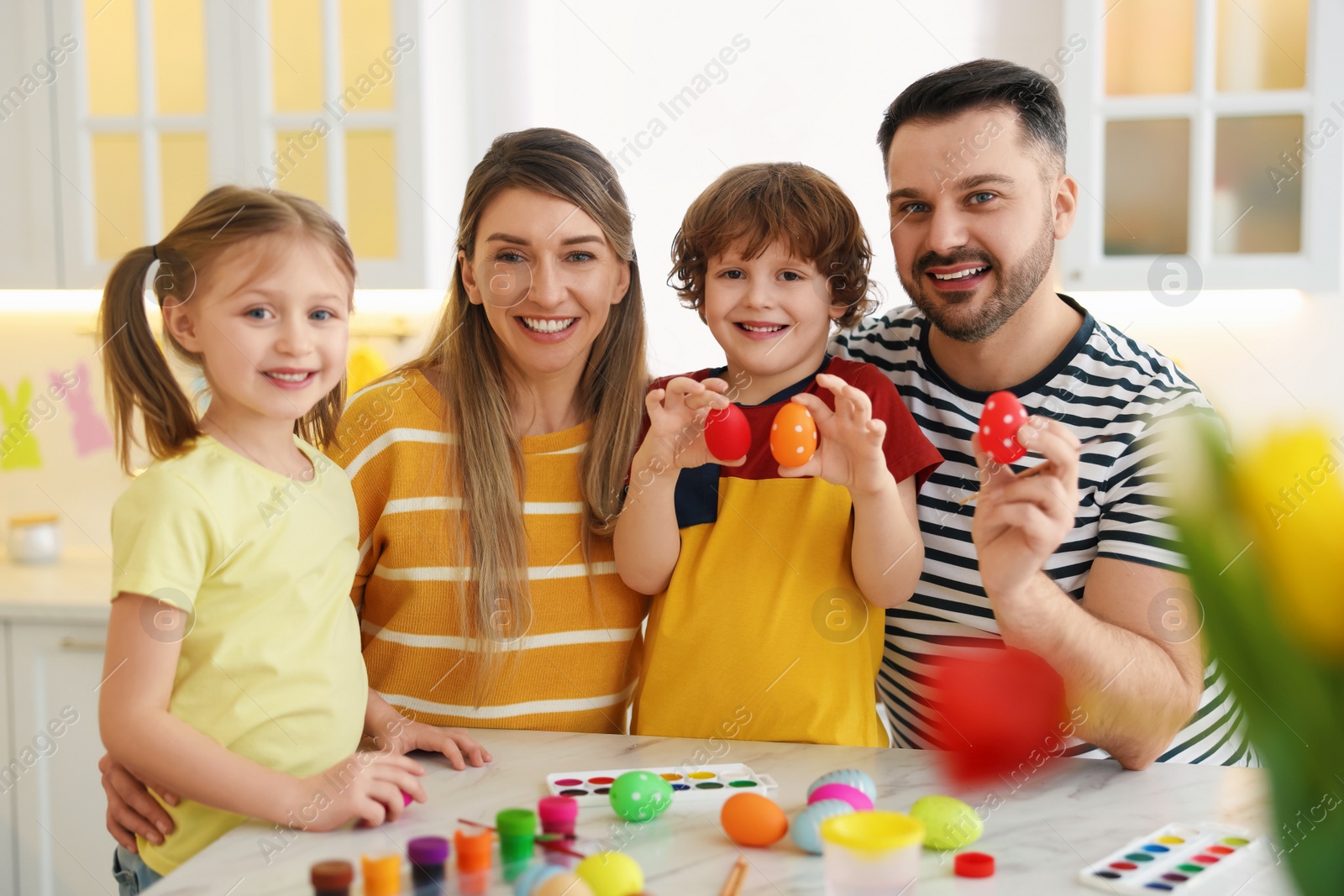 Photo of Easter celebration. Portrait of happy family with painted eggs at white marble table in kitchen