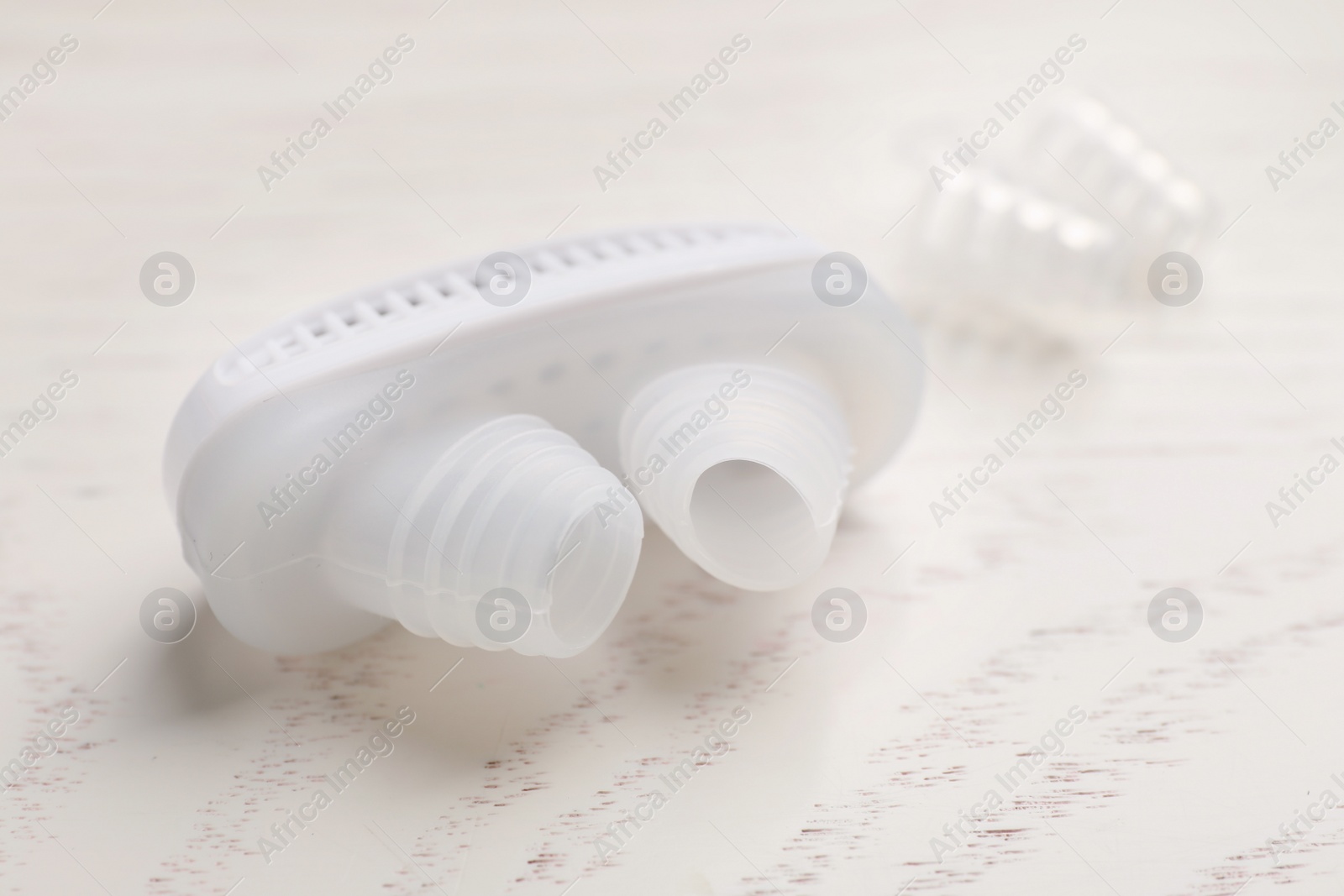 Photo of Anti-snoring device for nose on white wooden table, closeup