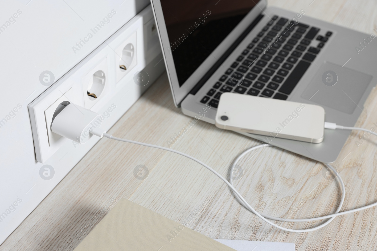 Photo of Laptop and smartphone charging on wooden table