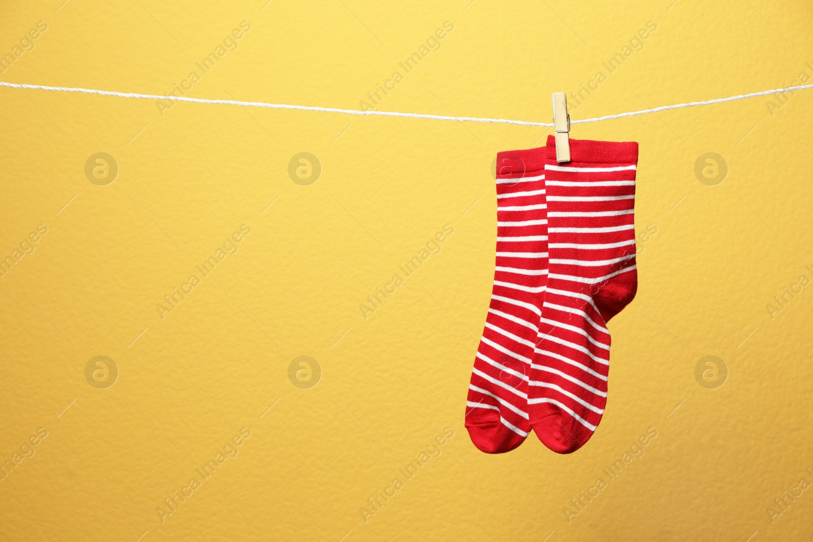 Photo of Cute socks on laundry line against color background. Space for text