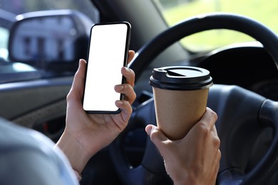 Photo of Coffee to go. Woman with paper cup of drink and smartphone in car, closeup