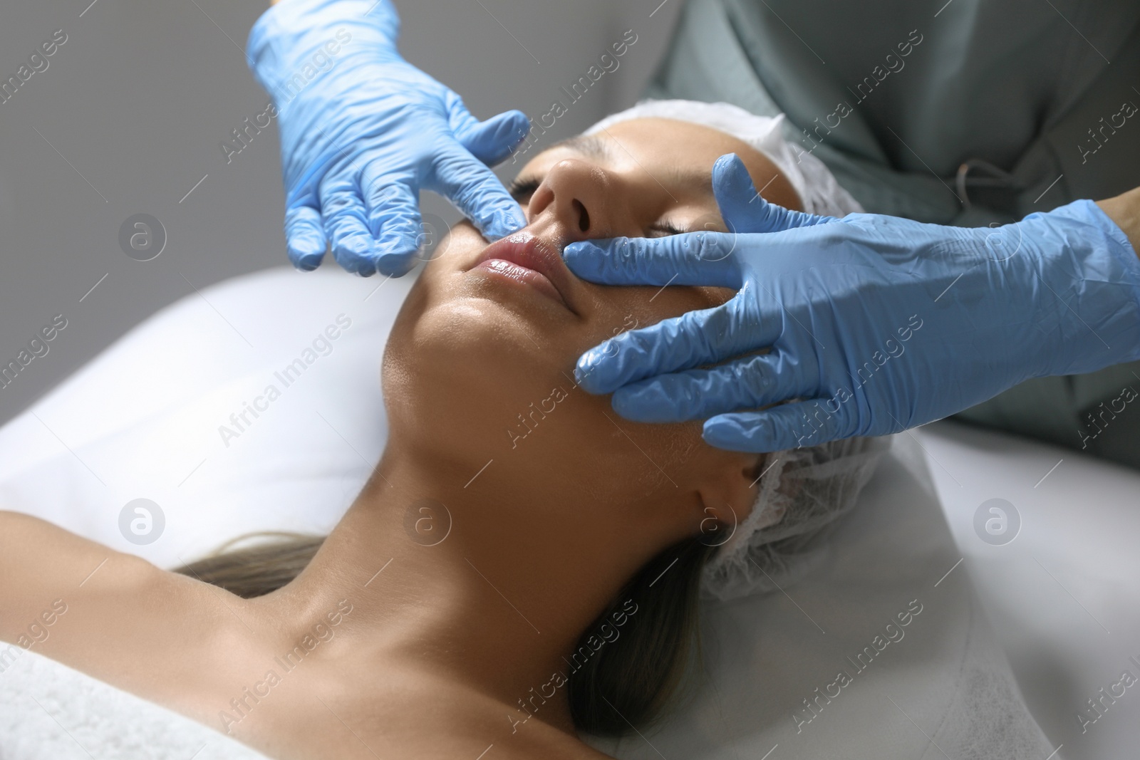 Photo of Young woman receiving facial massage in salon