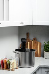 Pot with sous vide cooker and vacuum packed food products in kitchen. Thermal immersion circulator