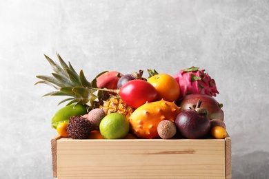 Photo of Crate with different exotic fruits on light grey background