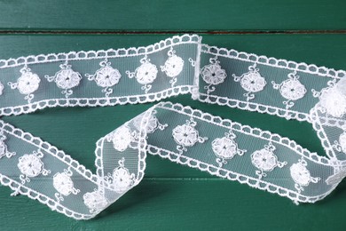 Photo of White lace on green wooden table, top view