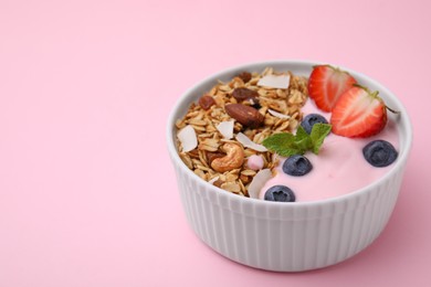 Photo of Tasty granola, yogurt and fresh berries in bowl on pink background, closeup with space for text. Healthy breakfast
