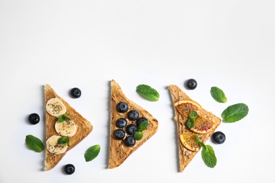 Photo of Different toasts with fruits, blueberries, peanut butter and chia seeds on white background, top view. Space for text