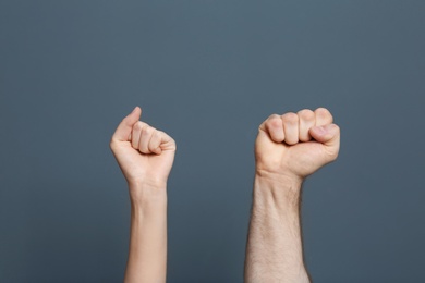 Photo of Man and woman showing clenched fists on color background