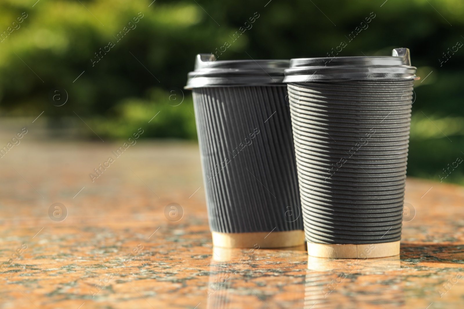 Photo of Paper coffee cups on stone parapet outdoors, closeup