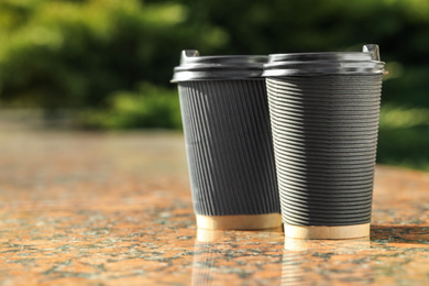 Photo of Paper coffee cups on stone parapet outdoors, closeup