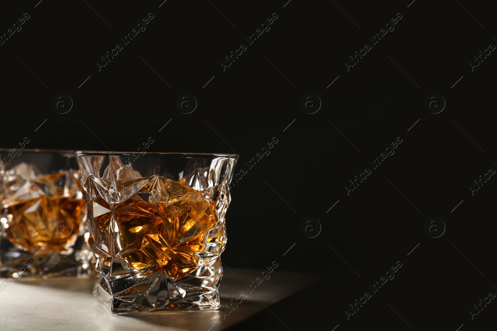 Photo of Golden whiskey in glass with ice cubes on table. Space for text