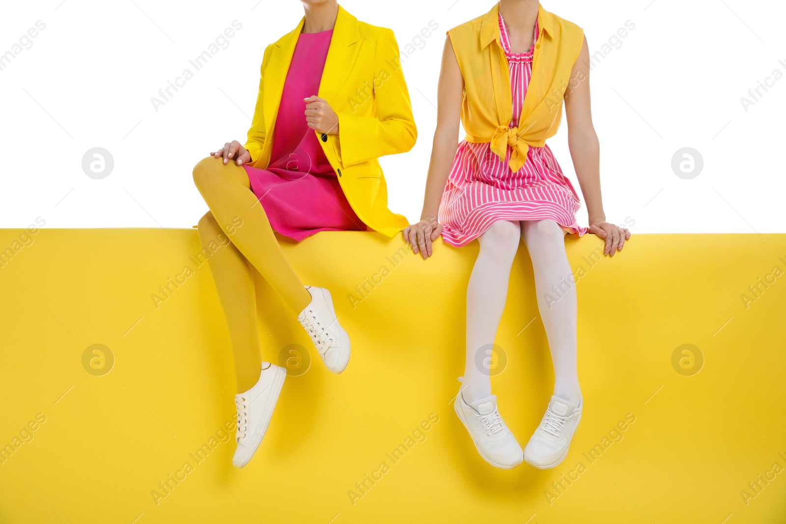 Photo of Women wearing bright tights sitting on color background, closeup