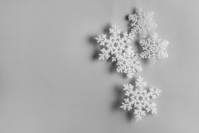 Beautiful decorative snowflakes hanging on light grey background, space for text