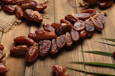 Photo of Branches with sweet dried dates and green leaf on wooden table