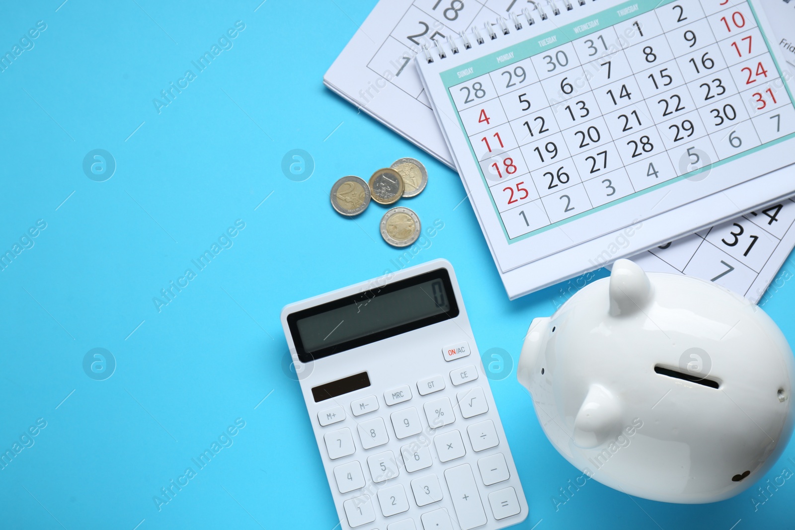 Photo of Flat lay composition with piggy bank and calculator on light blue background. Space for text