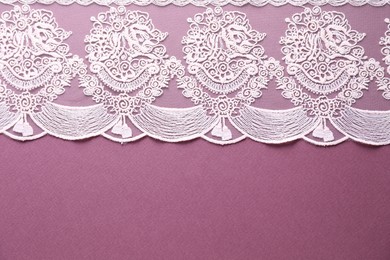 Photo of White lace on purple background, top view. Space for text